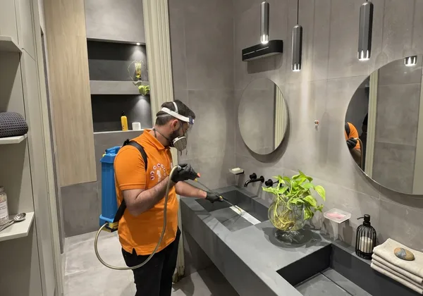 Best Control technician spraying a modern bathroom for pests in Erbil
